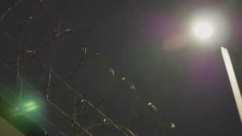Handheld shot of a barbed wire fence at night Vídeo Stock 263520114