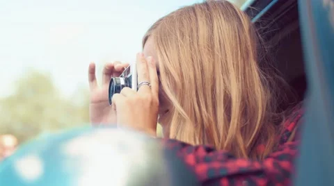 Handheld shot of blonde girl taking photo from car with a vintage film camera Stock Footage 55257553