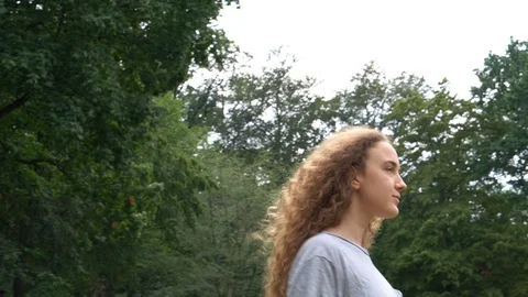 Handheld shot of blonde woman playing with her hair and walking in the park Stock Footage 114850153