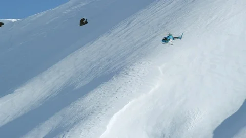 Handheld shot of blue helicopter flying above mountain covered in white snow Stock Footage 129128322