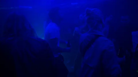 Handheld shot of camera winding through dancers on dance floor in low light 스톡 동영상 115090234