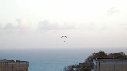 Handheld shot captures the thrill of paragliding over Bali's coastline at Video stock 278906212
