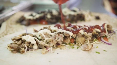 Handheld shot of chef hands in white gloves rolling chicken doner in pita 스톡 동영상 121852980