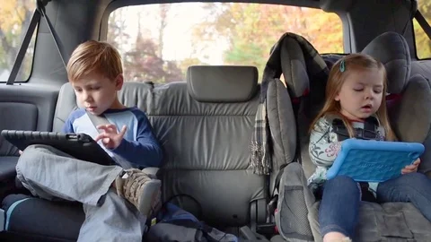 Handheld shot of children using tablet computers while traveling in car Stock Footage