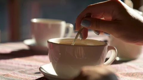 Handheld shot: Close up of hand mixing cappuccino coffee. HD Stockbeeldmateriaal 104054496