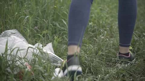 Handheld shot, close-up of plastic trash being dumped on the green grass Stock Footage 242091123