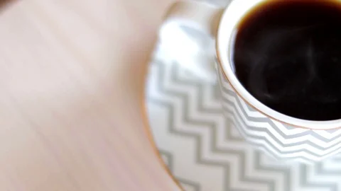 Handheld shot of coffee cup with coffee and steam rising in slow motion Video stock 114848786