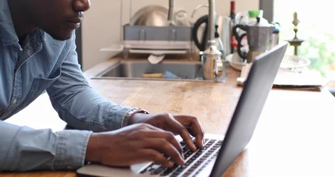 Handheld shot of concentrate man working on laptop in domestic kitchen Stock Footage 119794853