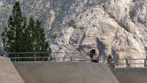 Handheld shot of construction workers on a dam with rocky mountain behind Stock Footage 122867636