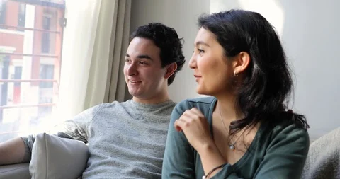 Handheld shot of couple talking while sitting together on sofa in living room Stock Footage 120419369