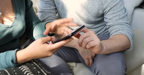 Handheld shot of couple using smart phone together while talking Stock Footage 120431544