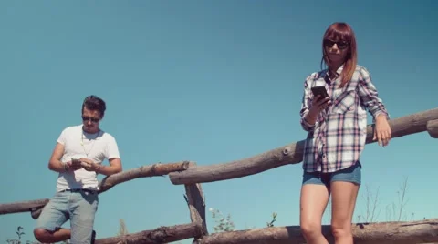 Handheld shot of couple using smartphone lean against wooden fence Stock Footage 55197268