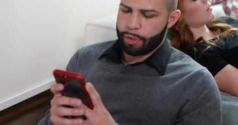 Handheld shot of couple using smartphones while relaxing in a living room Stock Footage 119751864
