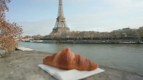 Handheld Shot of Croissant in Foreground with Eiffel Tower Paris France 스톡 동영상 324473106
