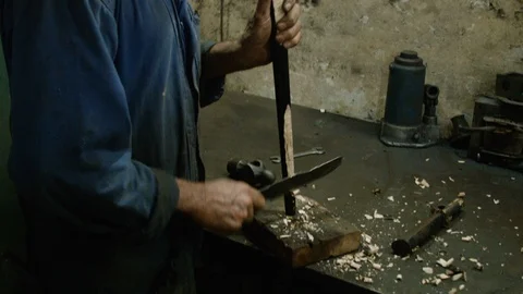 Handheld shot of elder Cuban man in workshop, cutting down wooden rod, Cuba Stock Footage 141659902