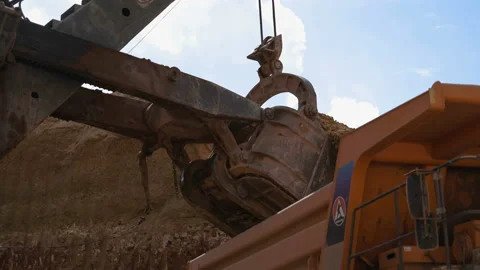 Handheld shot of excavator bucket loading ore into dump truck. Video stock 87727623