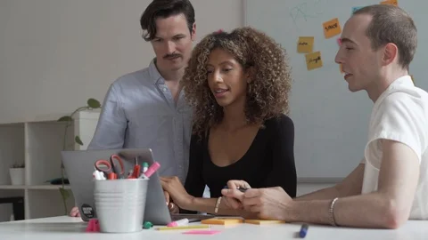 Handheld shot of executives discussing with each other while using laptop Stock Footage 114877876