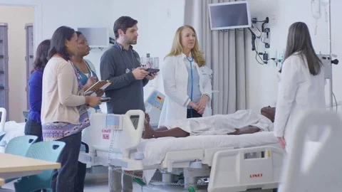 Handheld shot of female doctor training coworkers in hospital ward Stock Footage