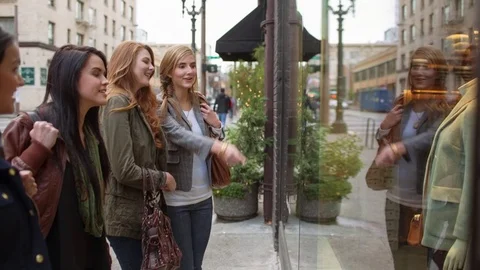 Handheld shot of female friends doing window shopping while standing against Stock Footage