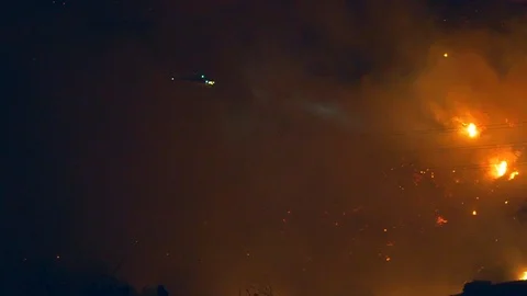 Handheld shot of a fire fighting helicopter, extinguishing wild fires, at Vidéo 121810052