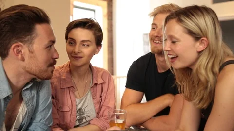 Handheld shot of four friends looking at phone and chatting with each other Stock Footage 114861981