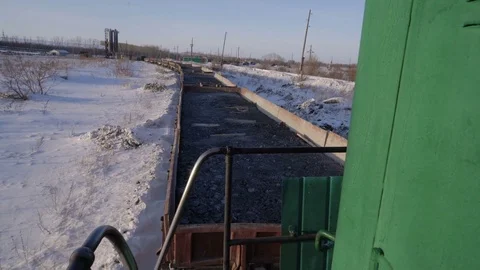 Handheld shot of freight train with empty gondola cars moving along a single Stock Footage 75265374