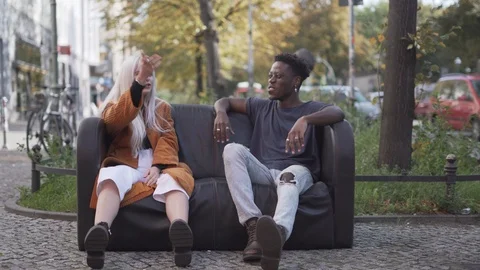 Handheld shot of friends talking while sitting on sofa outdoors Stock Footage 120419185