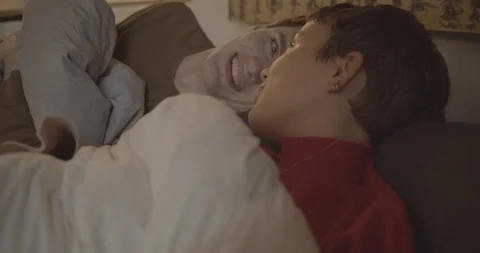 Handheld shot of friends talking while lying on bed in bedroom Stock Footage 120419746