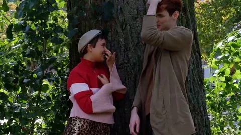 Handheld shot of friends talking while standing by tree trunk Stock-Footage 120420276