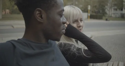 Handheld shot of friends talking while sitting in park Stock Footage 120456950