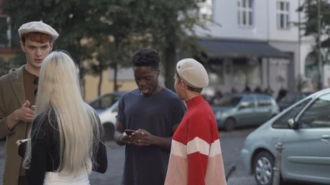 Handheld shot of friends using phone while standing on footpath Stock Footage 120423375