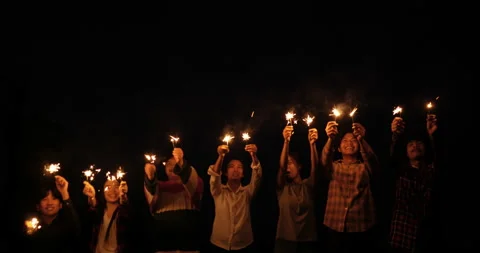 Handheld shot, Front view, Group of young friends stand in line holding fire  库存影片 221387972