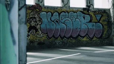 Handheld shot of a graffiti wall inside an abandoned warehouse Stock Footage 112896967