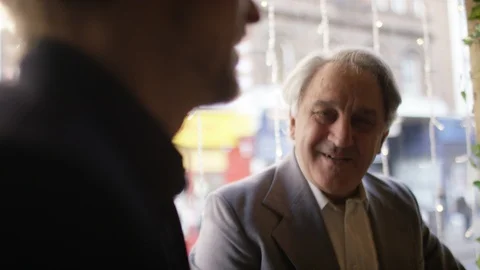 Handheld shot of a group of men at a table in a coffee shop or wine bar in conve Video stock 102424553