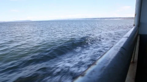 Handheld shot hanging off side of ferry, showing river and shore in distance. Stock Footage 86757861