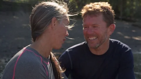 Handheld shot of happy couple talking while sitting at riverbank Stock Footage