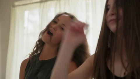 Handheld shot of happy female friends singing and dancing on bed at home Stock Footage
