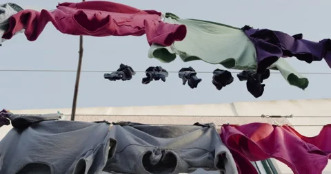Handheld shot of heavy clothes drying on piece of string outside in city Stock Footage 158714797