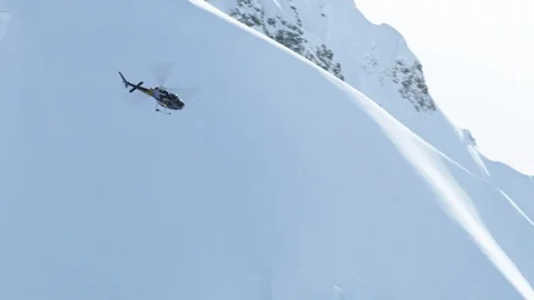 Handheld shot of helicopter flying around snowy surfaces of mountains Stock Footage 129111301