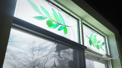 Handheld shot of kitchen windows featuring stained glass leaf patterns, casting Stock Footage 334634464