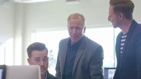 Handheld shot of male colleagues planning over desktop computer in office Stock Footage