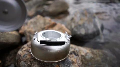 Handheld shot of a man closing and picking up the kettle from the river 스톡 동영상 114882602