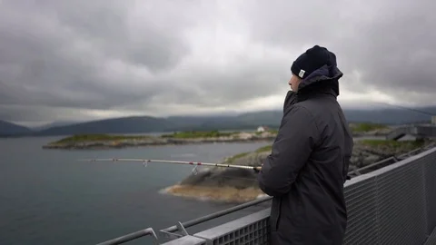 Handheld shot of a man fishing while standing at the railing 스톡 동영상 114882432