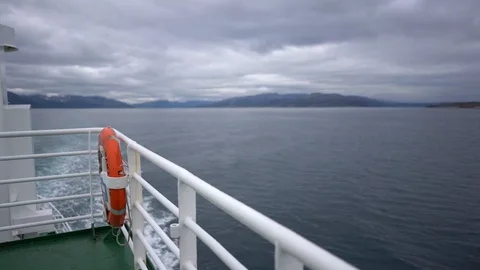 Handheld shot of a man leaning on the railing watching the coast Stock Footage 114883252