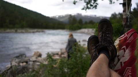 Handheld shot of a man lying in the hammock while her friend gets water Video stock 114882740