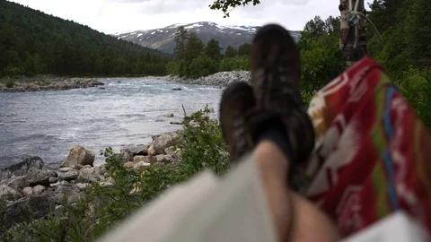 Handheld shot of a man lying in the hammock while her friend gets water Stock Footage 114882753