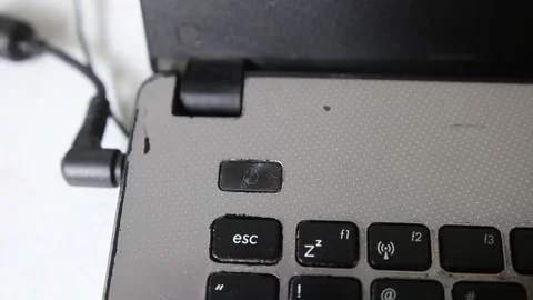 Handheld shot from a man pressing a on/off button on a old and beat-up laptop co Stock-Footage 228822647