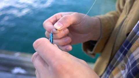 Handheld shot of a man tying fish bait for fishing Stock Footage 114882207