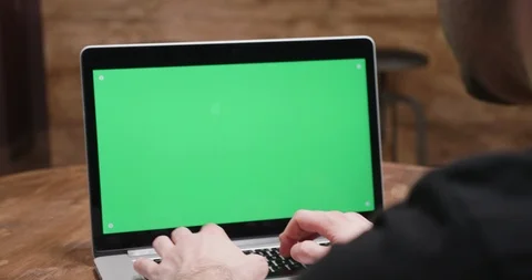 Handheld shot of man typing on a computer with green screen Stock Footage 104495110
