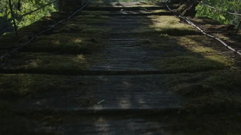 Handheld shot of man walking on a hanging bridge 库存影片 89866626